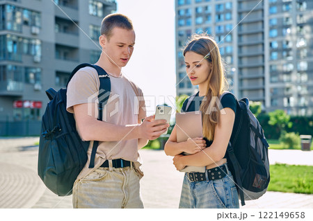 Young teenage guy and girl looking at smartphone together, urban background Young teenage guy and girl looking at smartphone together, urban background 122149658