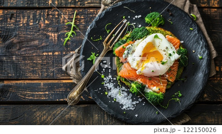 Deliciously prepared salmon with poached egg and broccoli on a rustic wooden table 122150026