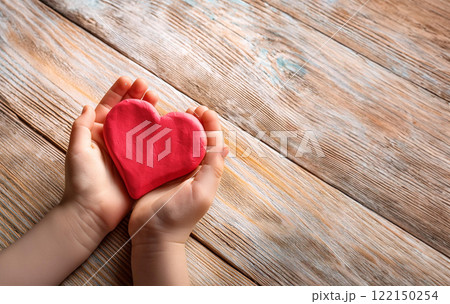 Child Hands Holding a Large Pink Clay Heart on Rustic Wood 122150254