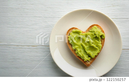 Heart Shaped Avocado Toast on White Plate with Wooden Background. Heart Shaped Avocado Toast on White Plate with Wooden Background. 122150257