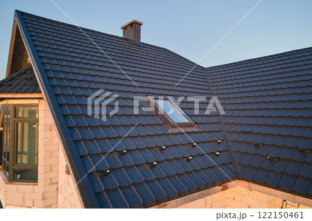 Closeup of attic window on house roof top covered with ceramic shingles. Tiled covering of building Closeup of attic window on house roof top covered with ceramic shingles. Tiled covering of building 122150461