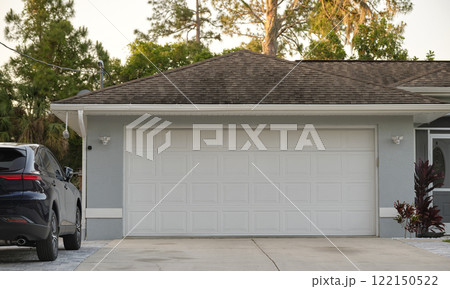 Car parked in front of wide garage double door on concrete driveway of new modern american house 122150522