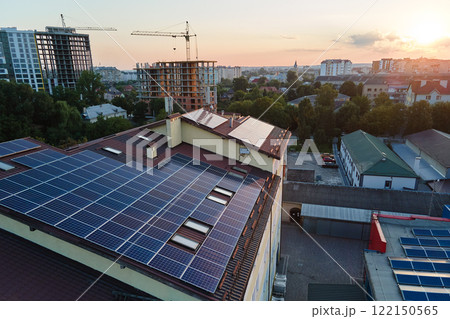 Blue photovoltaic solar panels mounted on building roof for producing clean ecological electricity at sunset. Production of renewable energy concept Blue photovoltaic solar panels mounted on building roof for producing clean ecological electricity at sunset. Production of renewable energy concept 122150565