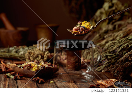 Various dried herbs and spices is poured into a glass teapot. Various dried herbs and spices is poured into a glass teapot. 122151521