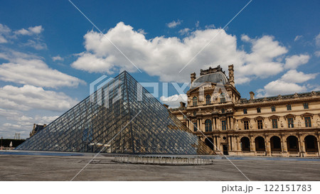 The Louvre Museum with its iconic glass pyramid under a bright blue sky 122151783
