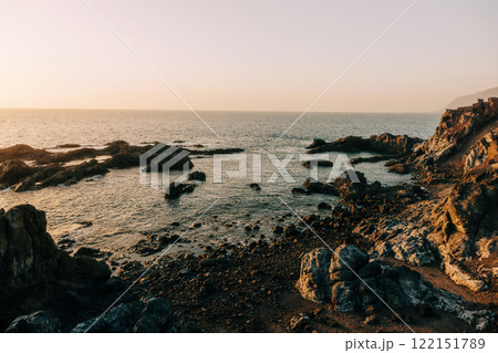 Rocky coastal landscape with calm sea and soft golden light Rocky coastal landscape with calm sea and soft golden light 122151789