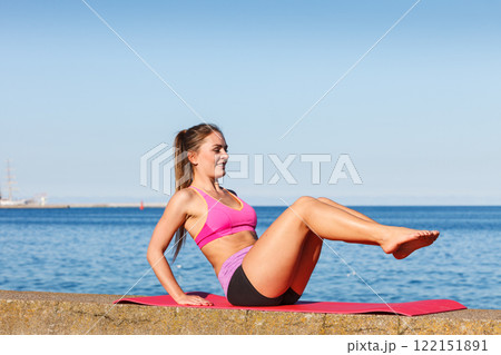 Woman doing sports exercises outdoors by seaside Woman doing sports exercises outdoors by seaside 122151891
