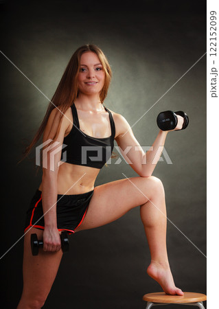 Fit woman exercising with dumbbells. 122152099