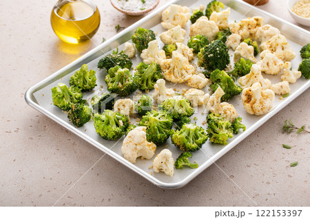 Broccoli and cauliflower ready to be roasted on a baking sheet with herbs Broccoli and cauliflower ready to be roasted on a baking sheet with herbs 122153397