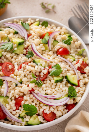 Pearl couscous salad with fresh vegetables and red onion 122153424