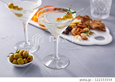 Traditional martini cocktail with olive garnish and charcuterie board 122153554