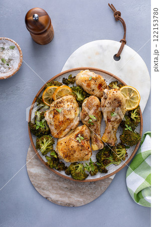 Chicken drumsticks and thighs with broccoli roasted on a serving plate for dinner or lunch Chicken drumsticks and thighs with broccoli roasted on a serving plate for dinner or lunch 122153780