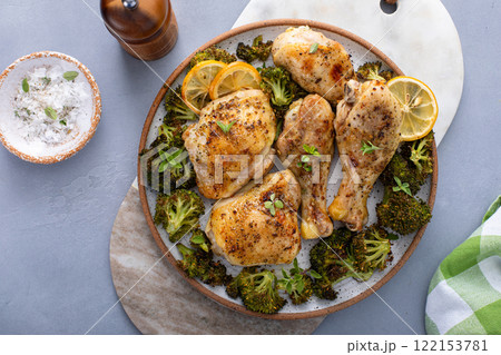 Chicken drumsticks and thighs with broccoli roasted on a serving plate for dinner or lunch Chicken drumsticks and thighs with broccoli roasted on a serving plate for dinner or lunch 122153781