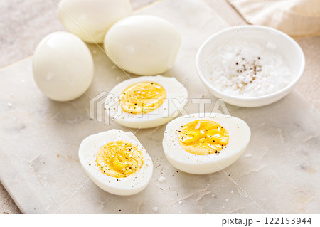 Boiled eggs peeled and cut in half with salt and pepper 122153944