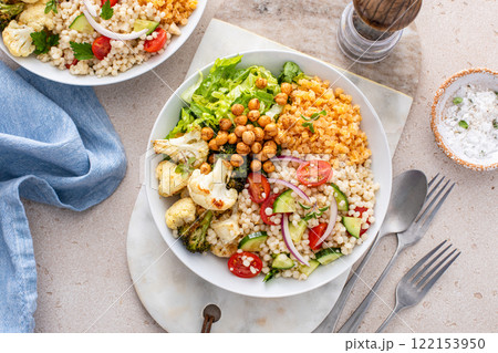 Vegan lunch bowl with roasted vegetables, fresh lettuce, cooked lentils, couscous salad and roasted chickpeas 122153950