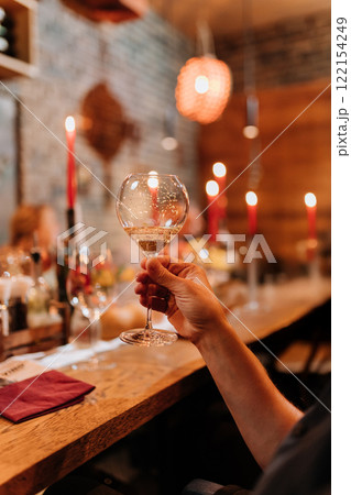 Raising a glass of sparkling wine in a warm, candlelit dinner setting for a festive celebration Raising a glass of sparkling wine in a warm, candlelit dinner setting for a festive celebration 122154249