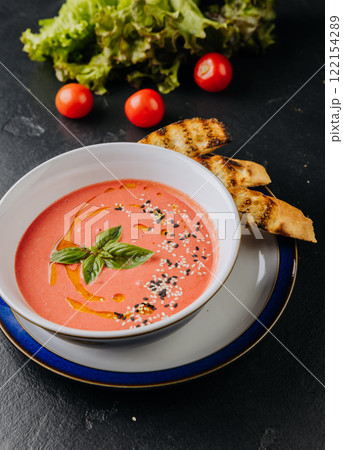 Fresh tomato soup with sesame seeds, basil garnish, and toasted bread for a comforting meal Fresh tomato soup with sesame seeds, basil garnish, and toasted bread for a comforting meal 122154289