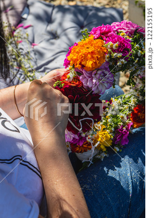 Pregnant woman weaving a floral wreath in a sunny garden at home 122155195