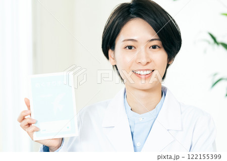 笑顔でお薬手帳を持つ女性薬剤師 122155399