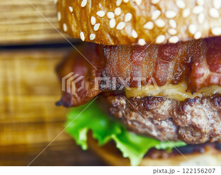 Delicious bacon cheeseburger with fresh lettuce served on a rustic wooden table at lunchtime. Generative AI Delicious bacon cheeseburger with fresh lettuce served on a rustic wooden table at lunchtime. Generative AI 122156207