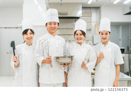 厨房・キッチンに立つコックコート姿の調理師・シェフ・コックの男女 厨房・キッチンに立つコックコート姿の調理師・シェフ・コックの男女 122156373