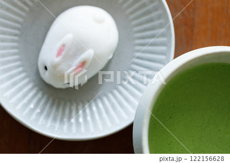 Cup of fresh matcha tea, green tea and Bunny Rabbit shape daifuku Japanese confectionery on wooden table. Cup of fresh matcha tea, green tea and Bunny Rabbit shape daifuku Japanese confectionery on wooden table. 122156628