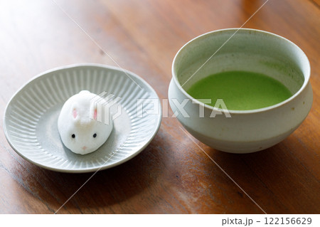 Cup of fresh matcha tea, green tea and Bunny Rabbit shape daifuku Japanese confectionery on wooden table. Cup of fresh matcha tea, green tea and Bunny Rabbit shape daifuku Japanese confectionery on wooden table. 122156629