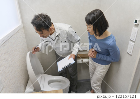 トイレの故障の修理を修理業者に依頼する女性 トイレの故障の修理を修理業者に依頼する女性 122157121