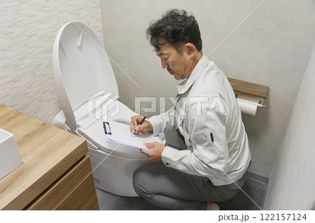 トイレの故障をチェックする修理業者の男性 122157124