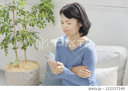 困りながらスマホを持つ中年女性 リビング 困りながらスマホを持つ中年女性 リビング 122157140