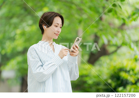 新緑の中で音楽を聴く女性 122157200