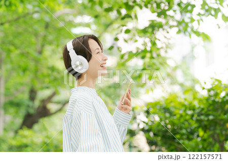 新緑の中で音楽を聴く30代女性 122157571
