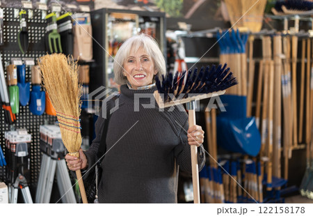 Mature woman choosing a broom Mature woman choosing a broom 122158178