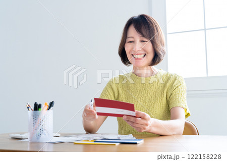 通帳を見ながら確定申告の準備をするミドル女性 122158228