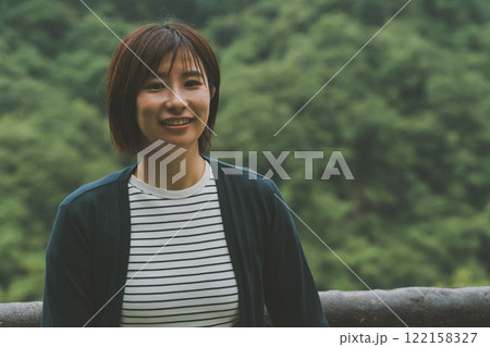 新緑に覆われた山と若い女性 122158327