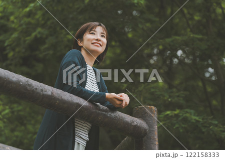 新緑に覆われた山と若い女性 122158333