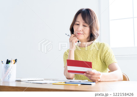 通帳を見ながら確定申告の準備をするミドル女性 122158426