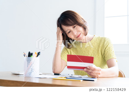 通帳を見ながら確定申告の準備をするミドル女性 122158429