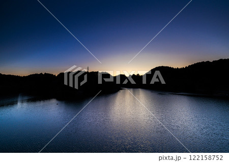 厳冬期の布目ダム小春日和の夕景　雲一つ無い空と美しい湖面　暗くなっていく空と半円形に残った夕焼け② 122158752