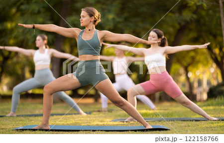Yoga lesson visitors girls perform ardha virabhadrasana in park 122158766