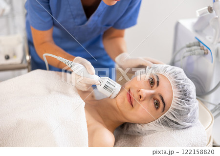 Female patient experiencing facial cryotherapy procedure in cosmetic clinic. 122158820
