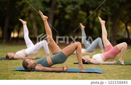 Group of young women doing yoga in park 122158843