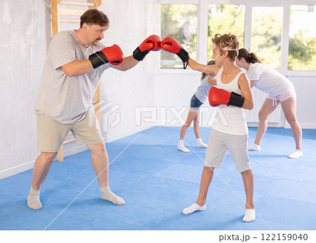 Boy and dad are boxing in gym, father helps child to work out force of blow. Boy and dad are boxing in gym, father helps child to work out force of blow. 122159040