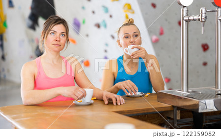 Two women drinking tea and chatting during break in bouldering gym 122159082