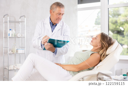 Male doctor carries out questionnaire survey of woman after procedure 122159115