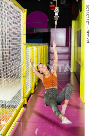 Excited woman swinging on indoor zip line at modern play center Excited woman swinging on indoor zip line at modern play center 122159159