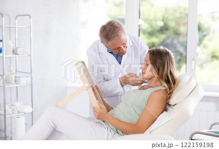 Elderly man doctor examining adult woman patient Elderly man doctor examining adult woman patient 122159198
