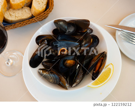 Steamed mussels served on table with piece of lemon Steamed mussels served on table with piece of lemon 122159212