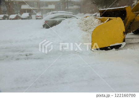 Snow accumulates in parking lot as snowplow works to clear area during winter storm. Snow accumulates in parking lot as snowplow works to clear area during winter storm. 122160700