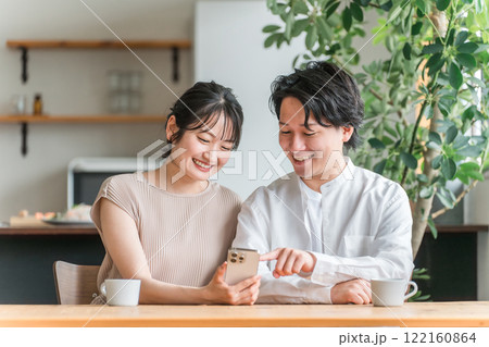 リビングダイニングでスマホを見る若いアジア人カップル 122160864